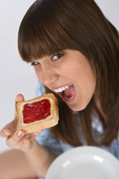 Happy teenager in pajamas eating healthy toast — Stock Photo, Image