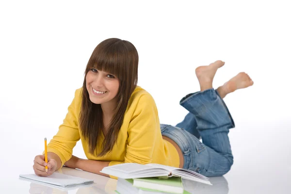 Glücklicher weiblicher Teenager schreibt Hausaufgaben — Stockfoto