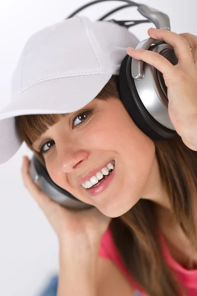 微笑女性青少年享受音乐在白色的背景 与耳机和棒球帽 — 图库照片