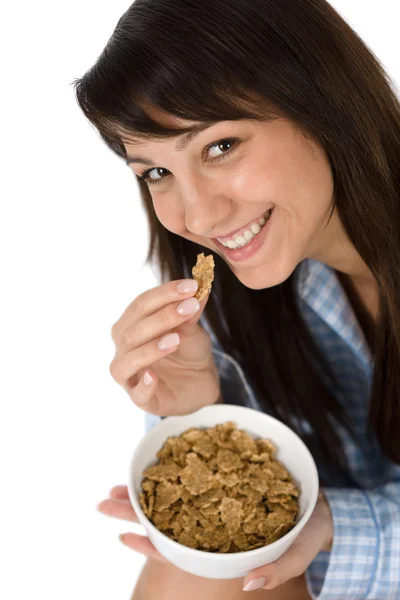 Une femme souriante mange des céréales de blé entier en pyjama — Photo
