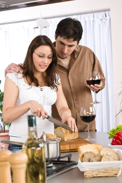 幸福的夫妻在一起在现代厨房喝红酒和切的面包 — 图库照片