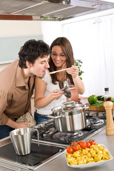 Paar kocht in Küche - Mann schmeckt Essen — Stockfoto