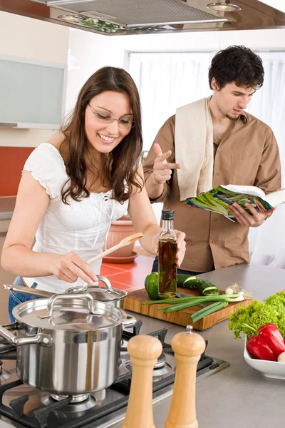 Casal feliz cozinheiro na cozinha com livro de receitas — Fotografia de Stock