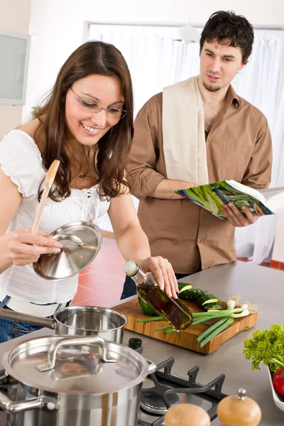 Happy couple cook in kitchen with cookbook — Stock Photo, Image
