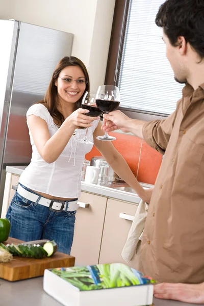 Jovem casal brindar com vinho tinto na cozinha — Fotografia de Stock