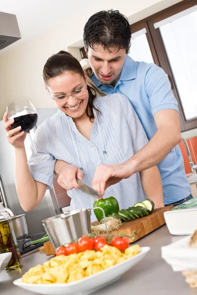 Счастливая пара режет овощи на кухне — стоковое фото