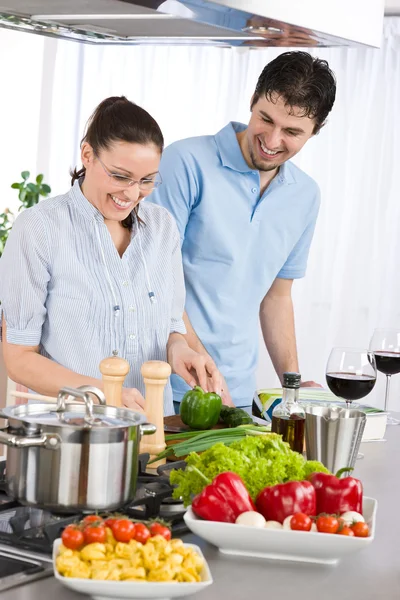 笑みを浮かべてカップル飲む赤ワインと野菜の台所で調理 — ストック写真