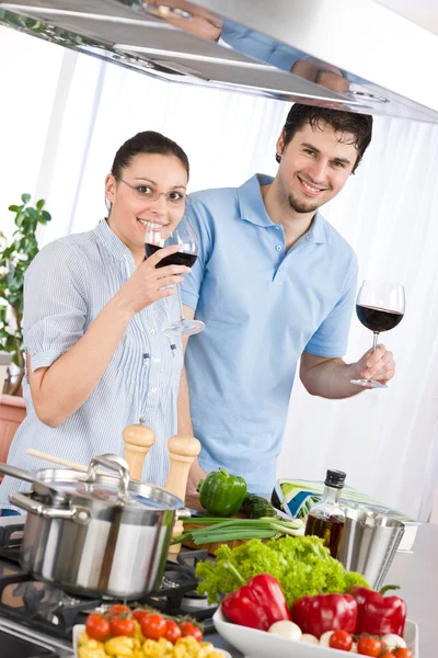 Χαμογελαστά, ζευγάρι πίνουμε κόκκινο κρασί το μαγείρεμα στην κουζίνα — Φωτογραφία Αρχείου
