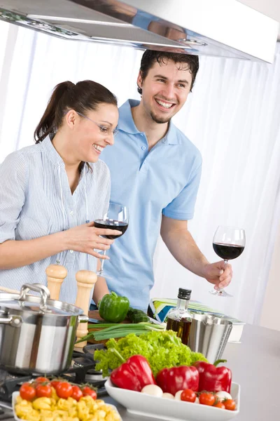 Casal sorridente beber vinho tinto cozinhar na cozinha — Fotografia de Stock