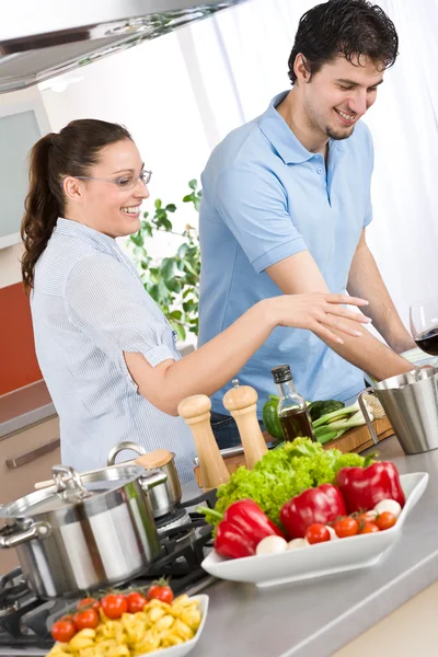 野菜とパスタと近代的なキッチンで料理をして笑顔のカップル — ストック写真
