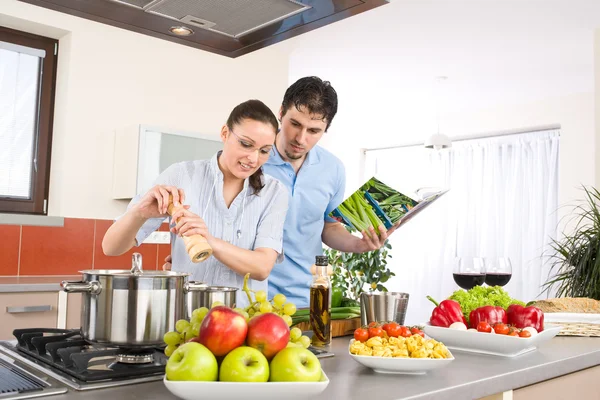 若い幸せなカップルの料理 パスタ 野菜の台所で調理します — ストック写真