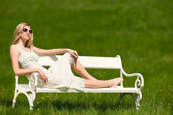 春 - 若い女性の牧草地でベンチでリラックス — ストック写真