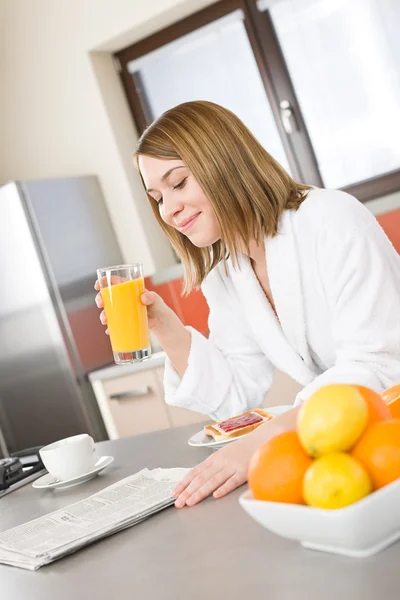 コーヒー 新鮮なオレンジ ジュース付きのキッチンで女性の読書新聞の笑みを浮かべて — ストック写真