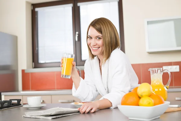 Colazione - Donna sorridente con succo d'arancia in cucina — Foto Stock