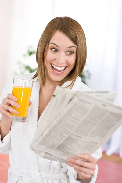 Breakfast - excited woman reading newspaper drink orange juice — Stock Photo, Image
