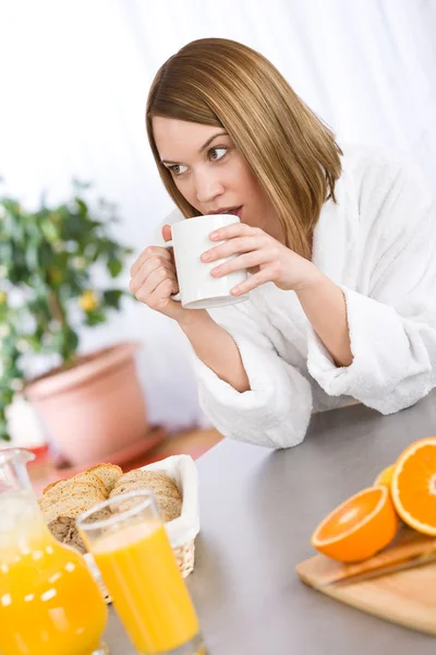コーヒーとモダンなキッチンにオレンジを持つ女性の笑みを浮かべて — ストック写真