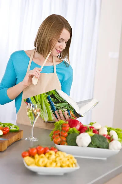 Кулінарія - жінка читає кулінарну книгу на кухні — стокове фото