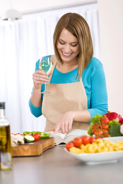 Cucina - Donna sorridente che legge la ricetta dal libro di cucina — Foto Stock