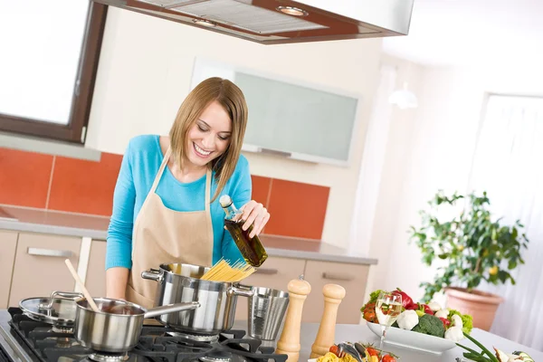 Koken - jonge vrouw met spaghetti op fornuis — Stockfoto