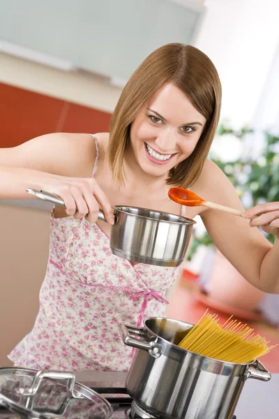 年轻女子品尝意大利番茄酱在现代的厨房里准备意大利面 — 图库照片
