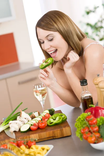 快乐的女人咬的现代厨房青椒切片 — 图库照片