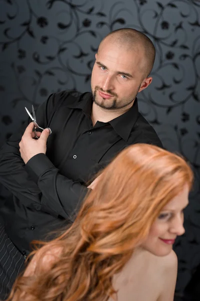 在黑色豪华沙龙 用剪刀剪头发红色的长卷发时装模特专业美发师 — 图库照片