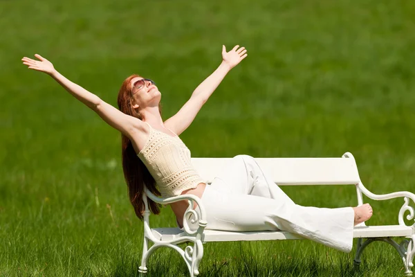 Frau mit rotem Haar genießt Sonne auf weißer Bank im Frühling — Stockfoto