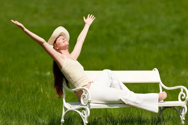 Capelli rossi donna godendo di sole sulla panchina bianca in primavera — Foto Stock