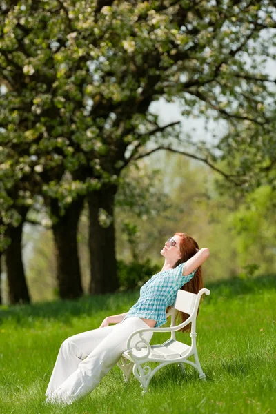 Junge Frau entspannt sich unter blühendem Baum im Frühling — Stockfoto
