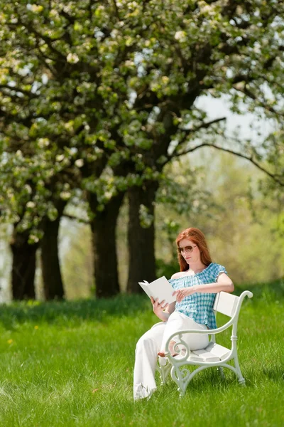 Ung kvinna avkopplande under blossom träd på våren — Stockfoto
