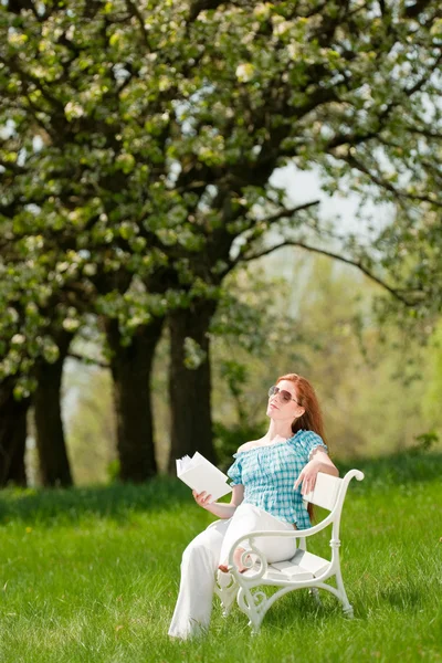 Genç kadın rahatlatıcı bahar çiçeği ağacının altında — Stok fotoğraf