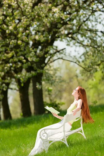 Ung kvinna avkopplande under blossom träd på våren — Stockfoto