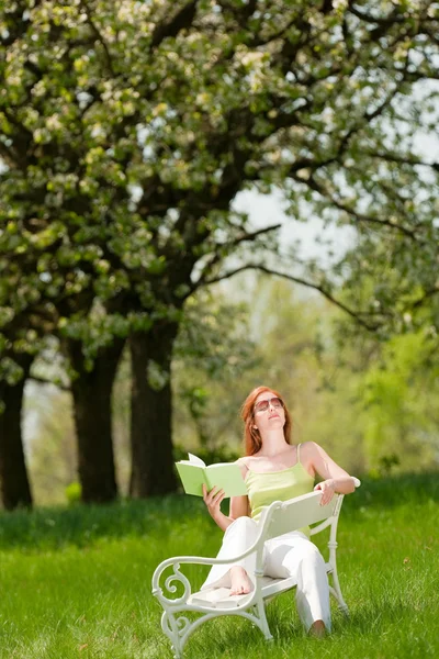 Junge Frau entspannt sich unter blühendem Baum im Frühling — Stockfoto