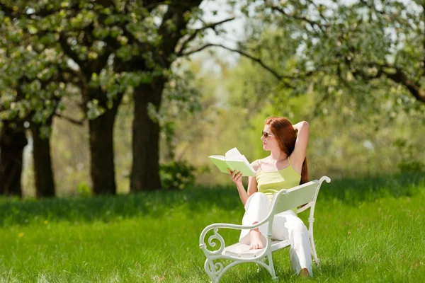 年轻女人放松下桃花树在春天 — 图库照片