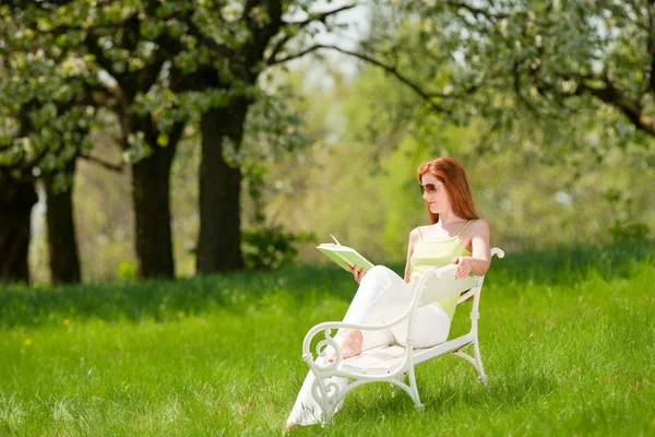 Mujer joven relajándose bajo el árbol de flores en primavera —  Fotos de Stock