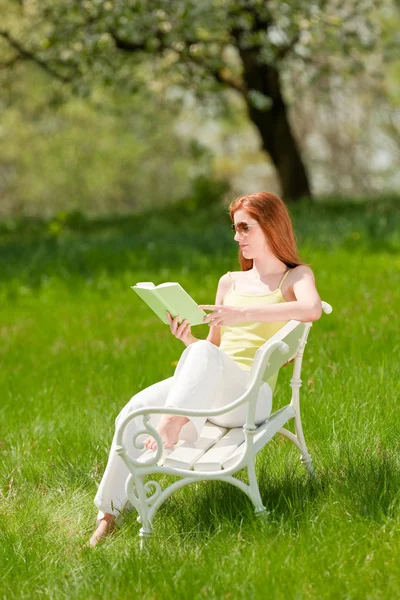 草原で白いベンチに座っている赤い髪の女性浅い被写し界深度 — ストック写真