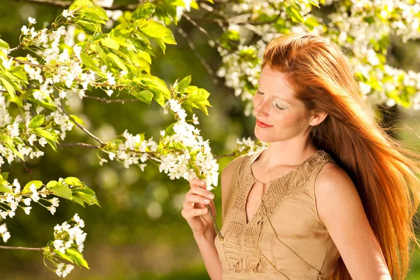 Молода жінка насолоджується весною під квітучим деревом — стокове фото