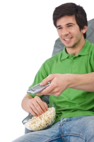 若い男持株リモコン テレビを見るし 手に白い背景に フォーカスにポップコーンを食べる — ストック写真