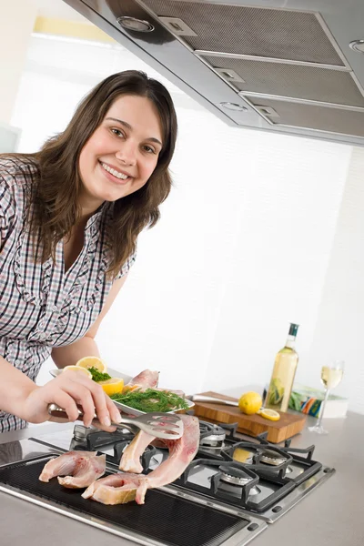Kuchařka - plus velikosti žena grilování ryb v kuchyni — Stock fotografie
