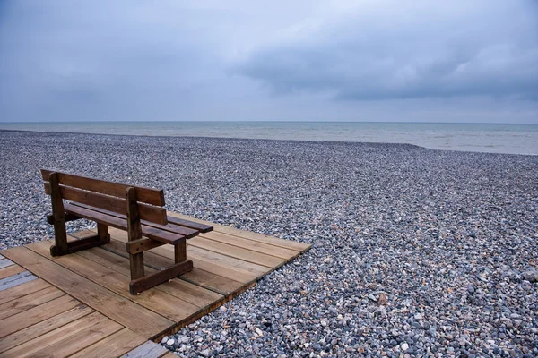 小石のビーチで木製のベンチ — ストック写真
