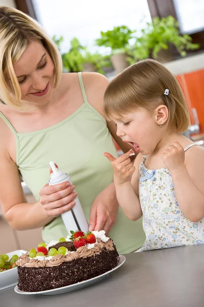 Мать и ребенок с шоколадным тортом на кухне — стоковое фото