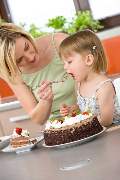 Matka a dítě ochutnávka čokoládový dort v kuchyni — Stock fotografie