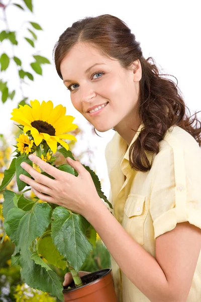 Smiling woman holding flower pot with sunflower — Stock Photo, Image