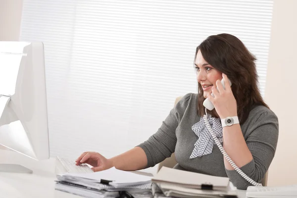 在办公室的电话上有吸引力的行政女人 免版税图库图片