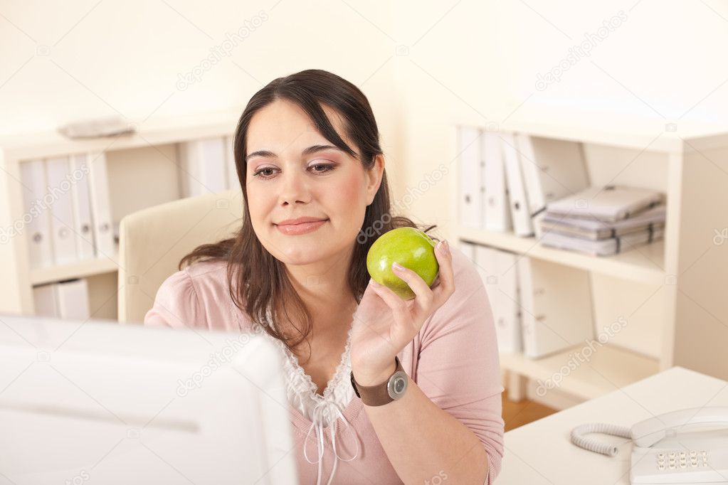 Young happy businesswoman holding apple at office