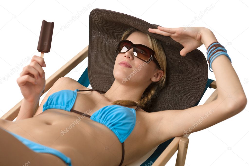 Beach - Attractive woman with hat and ice lolly sitting on deck chair in bikini