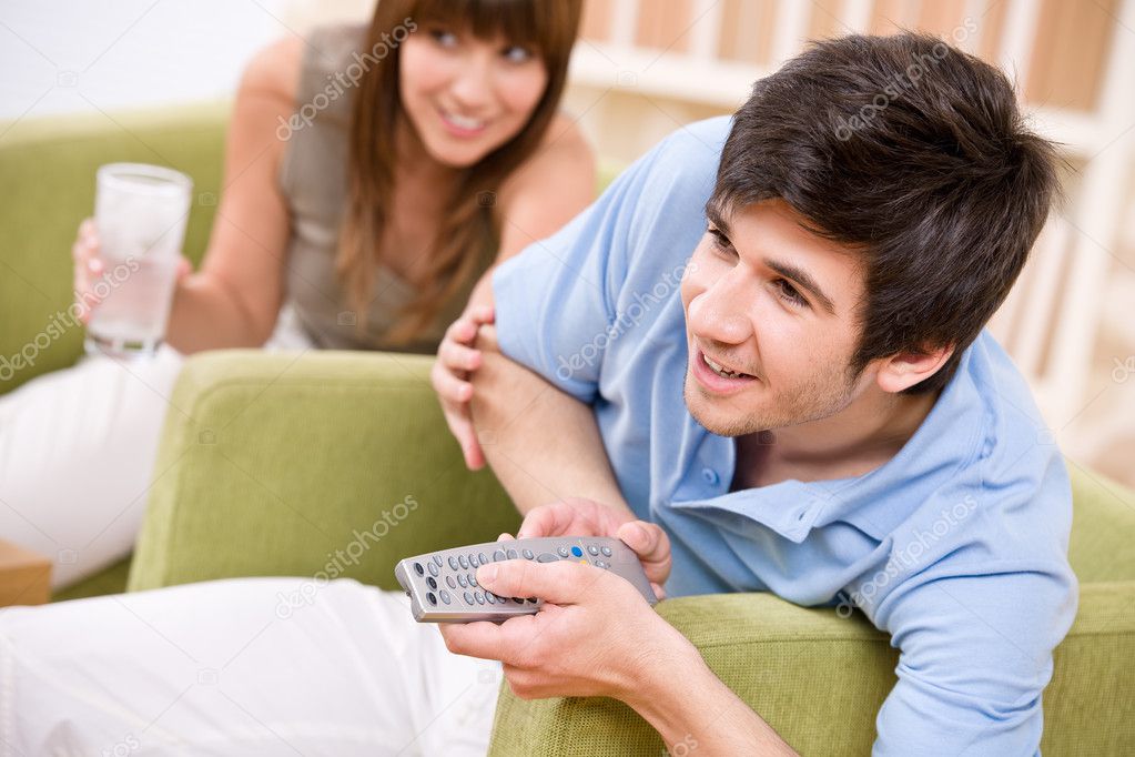Student - happy teenagers watching television holding remote control
