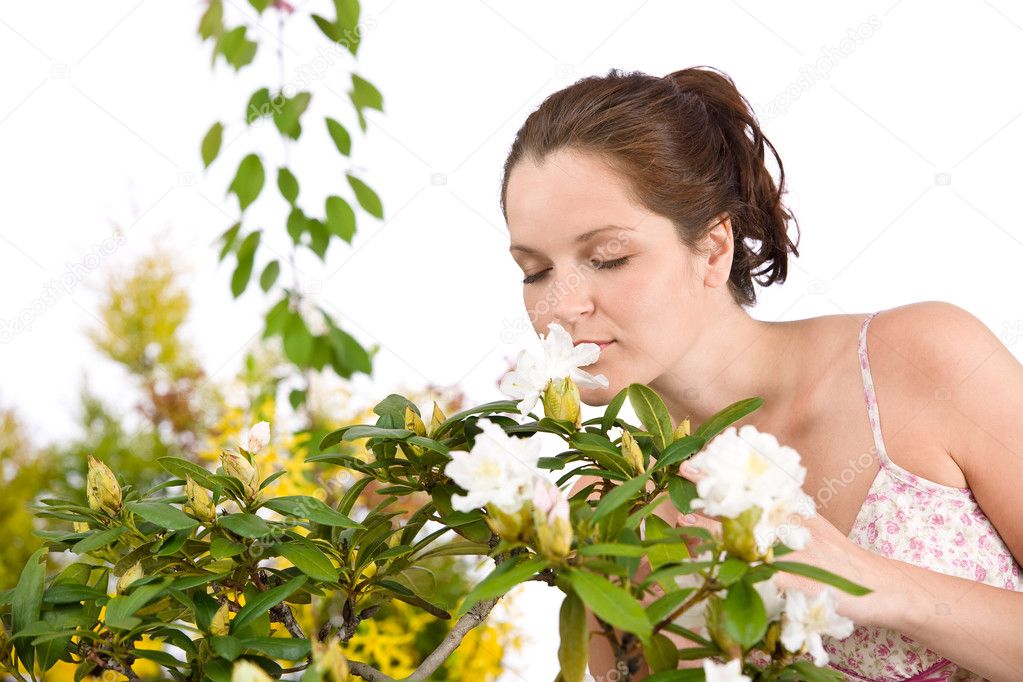 Portrait of woman smelling blossom of Rhododendron flower on white background
