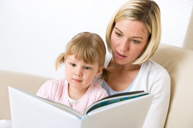 Mother with little girl read book together clipart