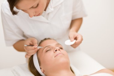 Luxury cosmetics - woman having facial, beautician using tweezers clipart